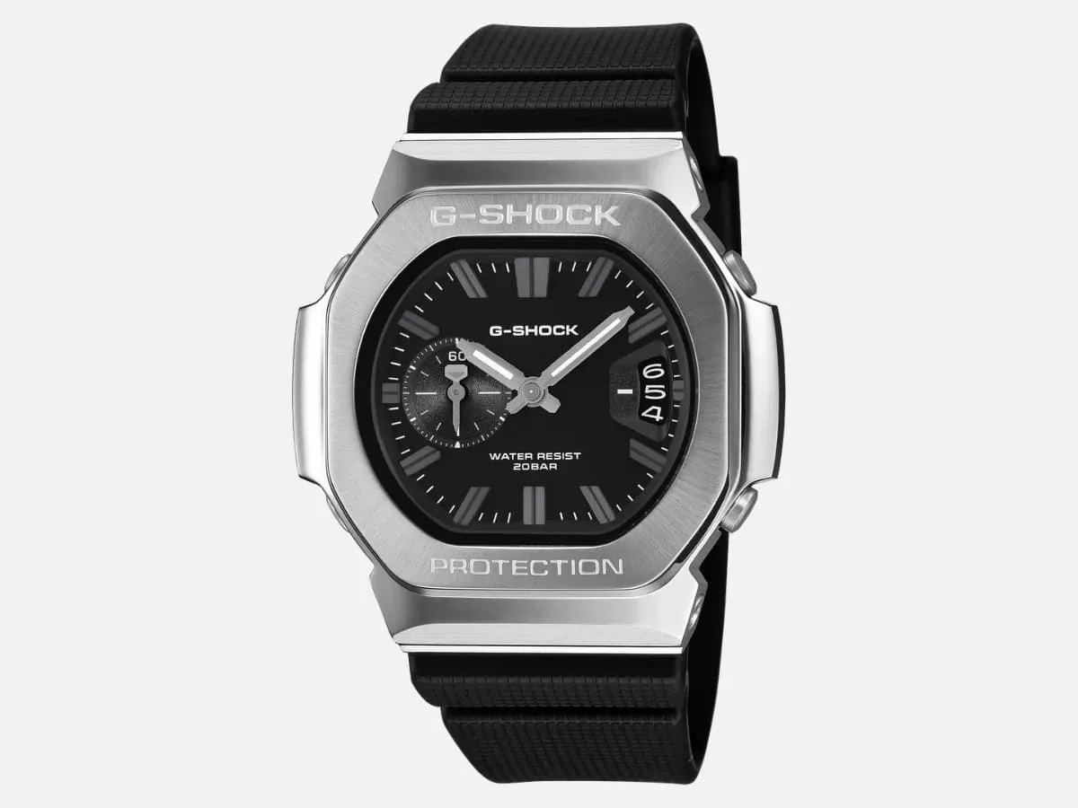 GMC-2500 black dial on the black resin strap. Caption: “The sensible middle. Steel where you see it, resin where it touches you — which matters in May.”