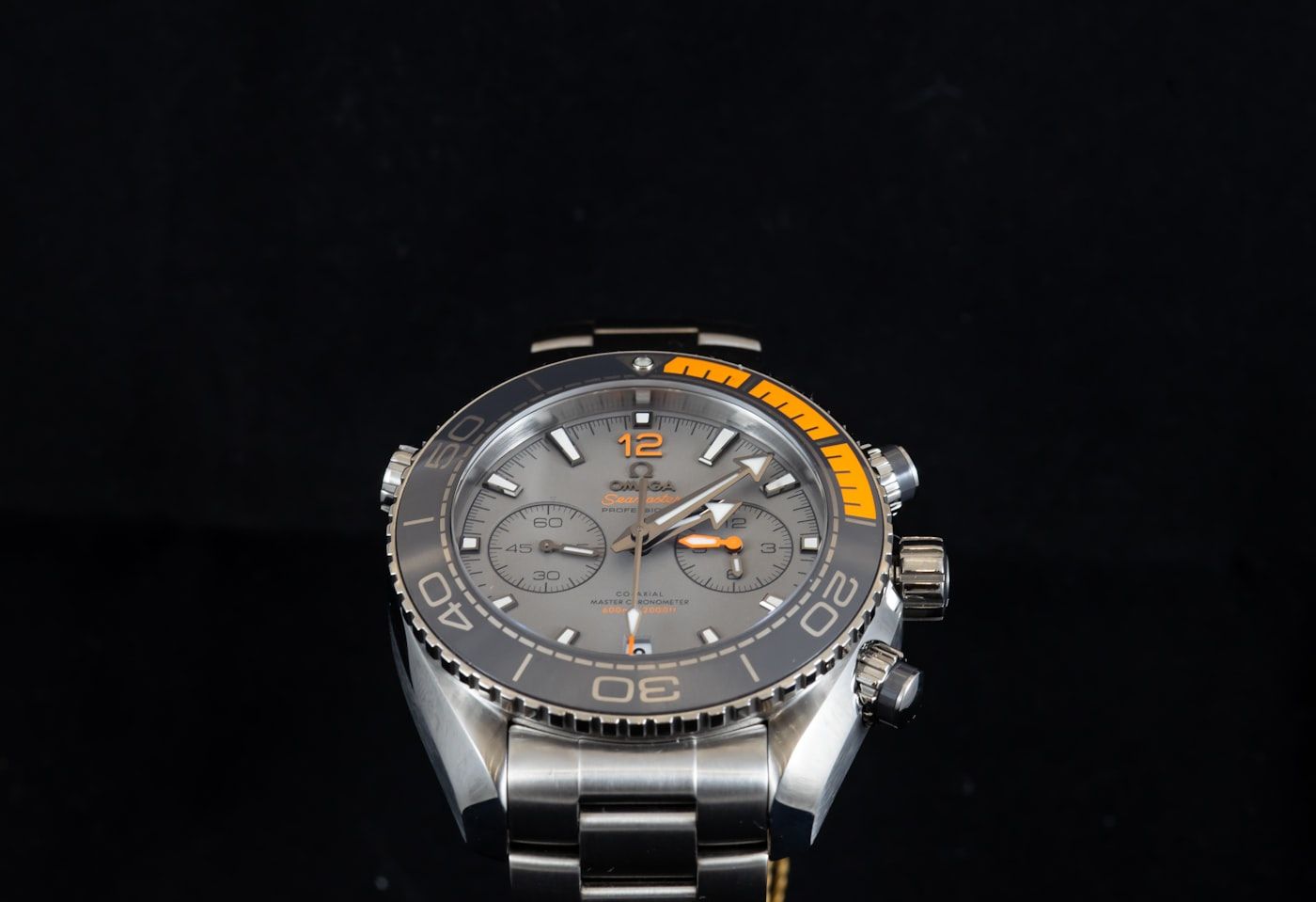 An automatic dive watch with an orange-accented rotating bezel on a dark background.